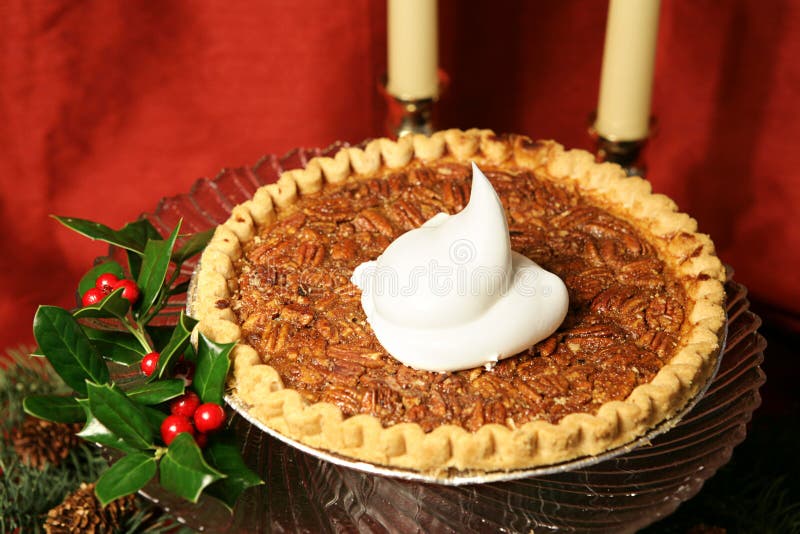 Chutné pecan pie ozdobené holly a dollop z šľahačkou, fotografoval proti prehodil červeného hodvábu v pozadí.