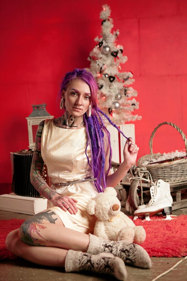 Christmas photo of a girl with purple dreadlocks and tattoos in the studio