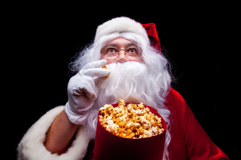 Christmas. Photo of Santa Claus gloved hand With a red bucket with popcorn, on a black background