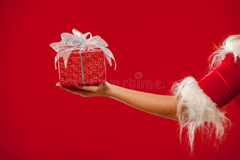 Christmas. Photo of Santa Claus gloved hand with red gift box