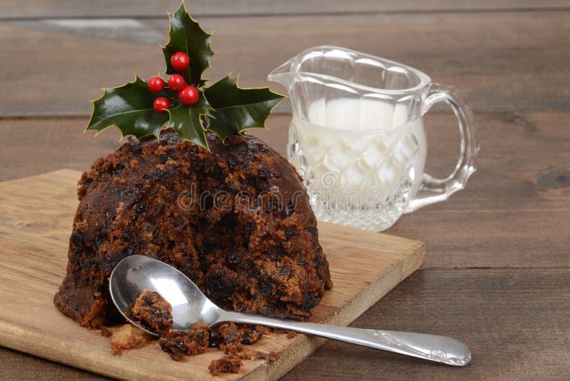 Christmas pudding on a cutting board with cream