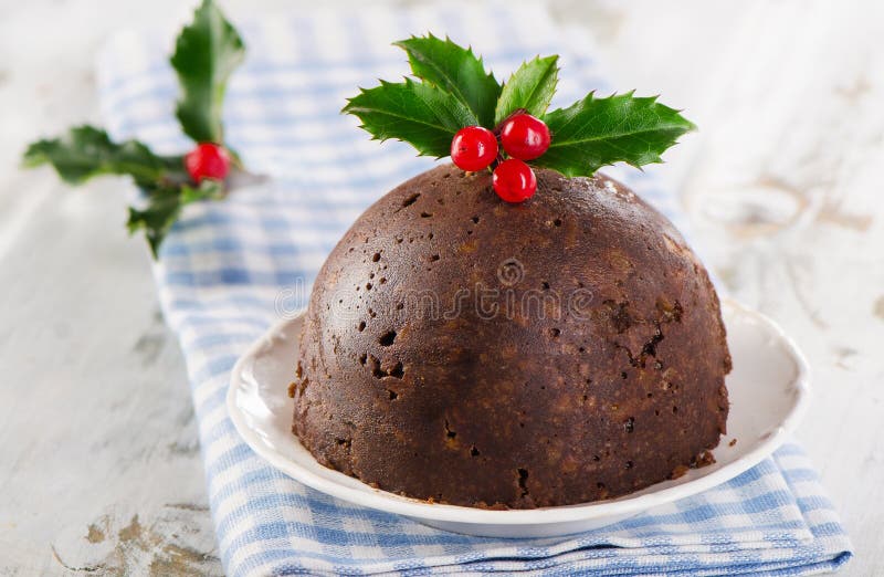 Christmas pudding with holly on a white plate.