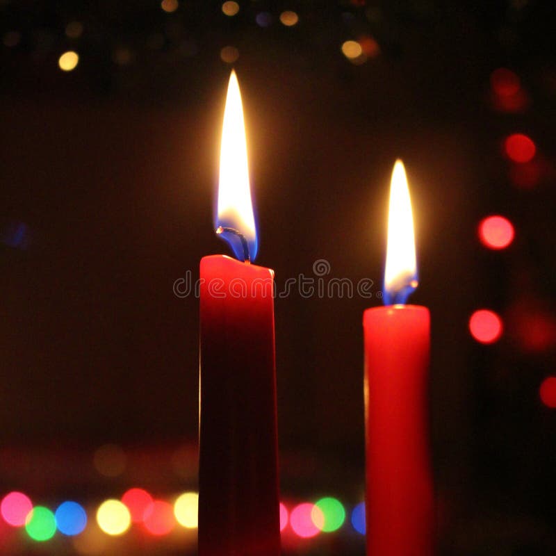 Two Candles Glowing in Front of the Distance Christmas Lights Stock