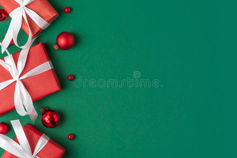 Christmas red gift boxes on green background. Christmas composition with decorations and holiday presents. Flat lay