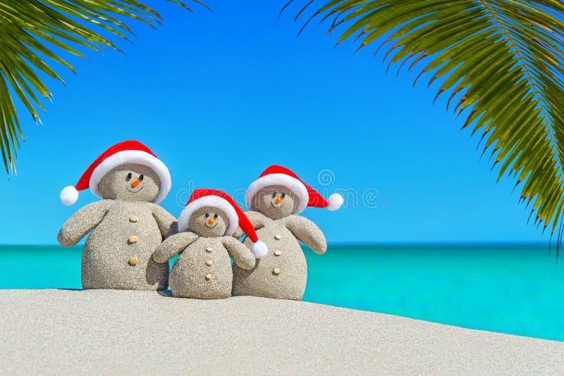 Christmas sandy Snowmen family in Santa hats at palm beach.