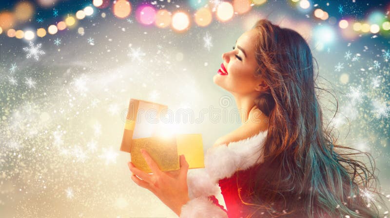 Christmas scene. Beauty brunette young woman in party costume opening gift box