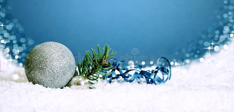 Christmas silver bauble and snow on blue .