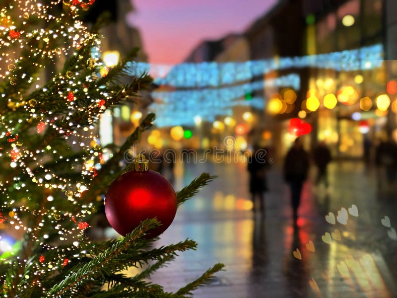 Christmas street life in the city ,green tree decorated with red balls and illumination,people walking  ,holiday travel to Medieva