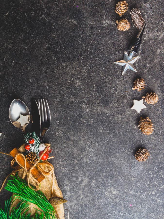 Christmas table place setting, cutlery in burlap bag with festive decorations star, cinnamon stick, pinecone with snow, berries