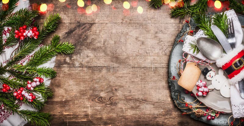 Christmas table place setting with festive decor, plate, cutlery , handmade snowman and blank tag on rustic wooden background, top