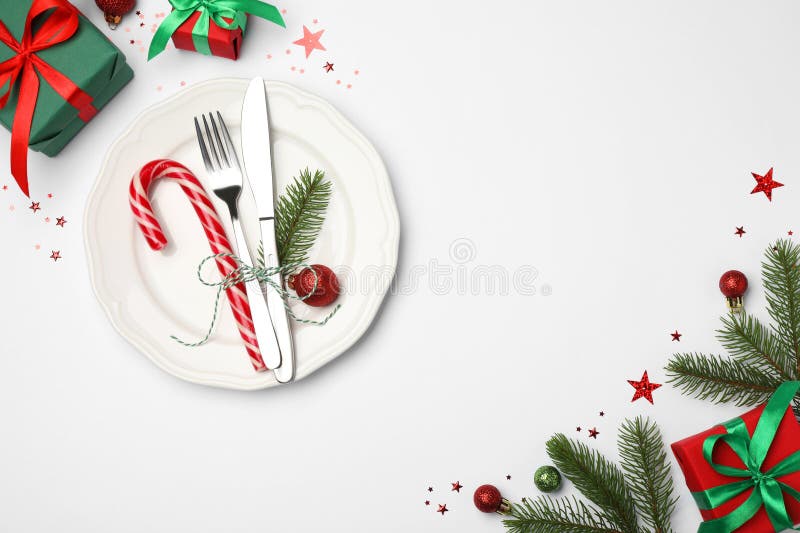 Christmas table setting with plate, cutlery and festive decor on white background, flat lay. Space for text