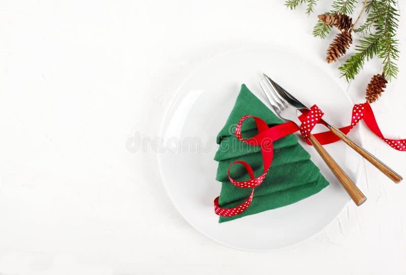 Christmas table setting with white plates and green Christmas tree napkin fold on white background 免版税库存图片 Christmas table setting with white plates and green Christmas tree napkin fold on white background 免版税库存图片