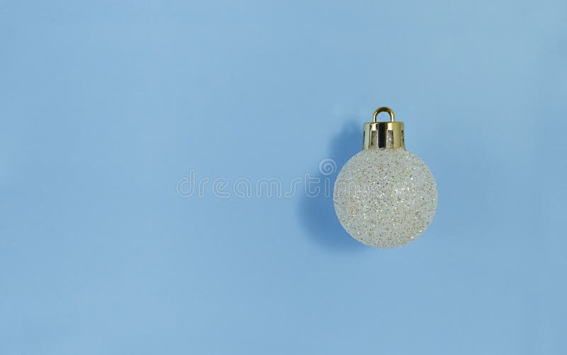 Christmas tree ball on a blue paper. Simple flat lay with copy space royalty free stock photo