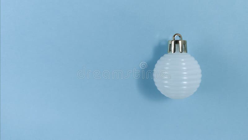 Christmas tree ball on a blue paper. Simple flat lay with copy space stock image