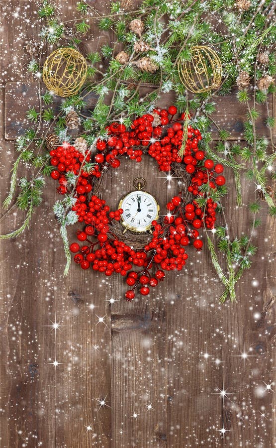 Green christmas tree branches and wreath from red berries over rustic wooden background. festive decoration with snowflakes effect