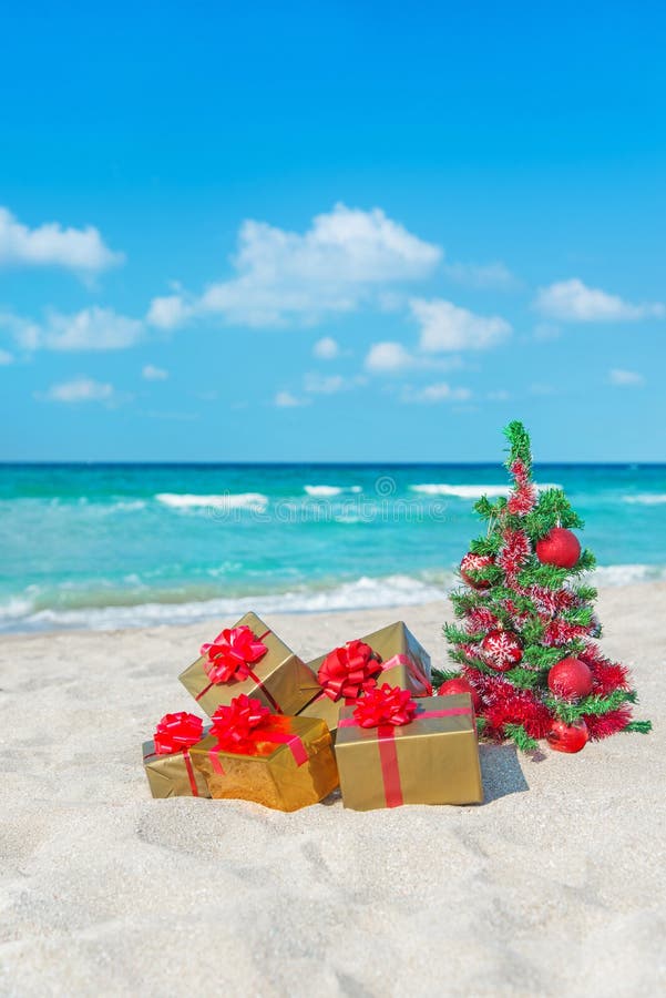 Christmas tree and golden gift with big red bow on the sea beach