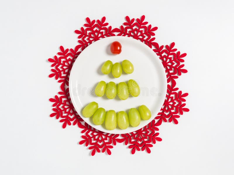 Christmas tree made of grapes and cherry tomato on white plate