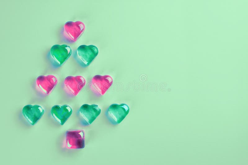 Christmas tree made of pink and green decorative glass hearts. Laying on trendy mint background. MInimal flat lay 2020 New Year holiday concept, elements, congratulation, bright, colorful, shiny, poster, event, paper, christmass, cristmas, symbol, postcard, ornament, above, idea, greeting, happy, design, abstract, merry, view, neo, creative, winter, top, december, xmas, love, modern