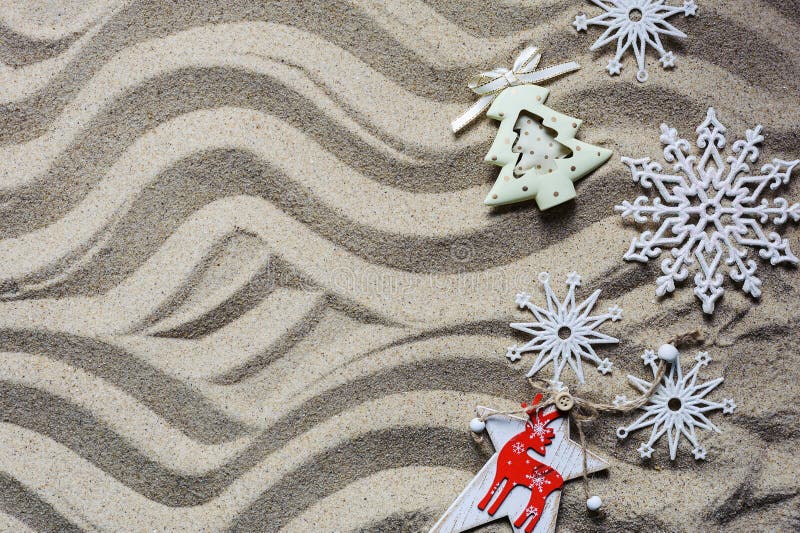 Christmas tree and snowflakes lie on the sea sand
