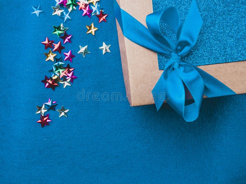 Christmas, weeding, Valentine day gift box or present with bow ribbon on trendy magic blue background, colorful stars. Sale concept. Copy space for greeting text. Christmas, weeding, Valentine day gift box or present with bow ribbon on trendy magic blue background, colorful stars. Sale concept. Copy space for greeting text