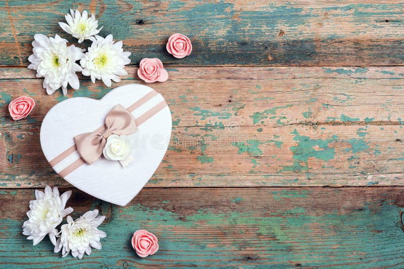 Chrysanthemum and rose flowers with heart shaped gift box on old wooden background