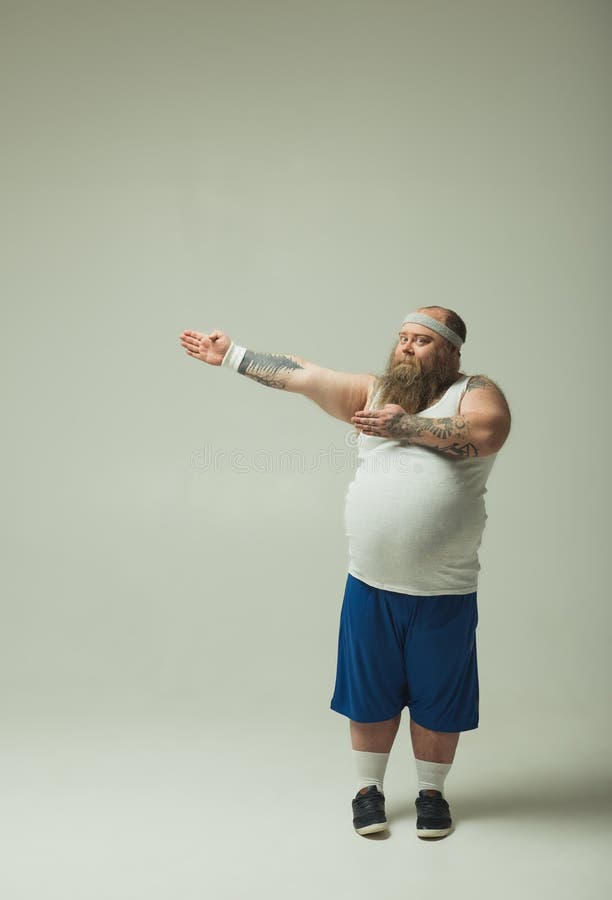 Chubby guy in sportswear showing the way by arms royalty free stock image Chubby guy in sportswear showing the way by arms royalty free stock image
