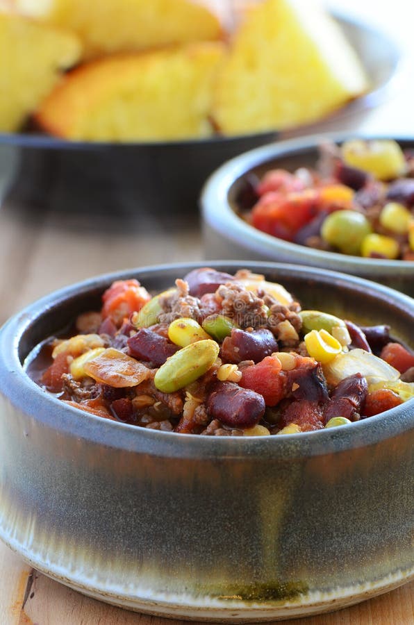 Hearty bowls of chuckwagon chili con carne with beef, beans, corn, tomato and cornbread