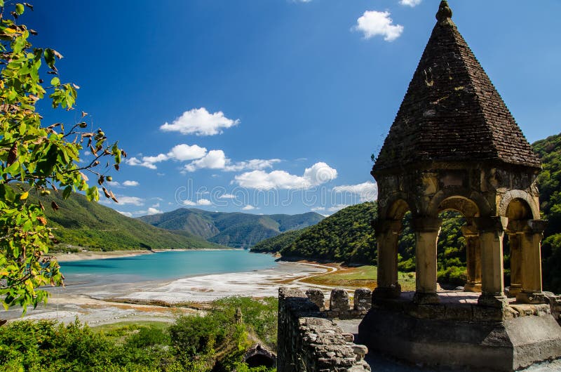 Church of the Mother of God, Ananuri with Zhinvali reservoir in the background and blue sky with few clouds above. Church of the Mother of God, Ananuri with stock image Church of the Mother of God, Ananuri with Zhinvali reservoir in the background and blue sky with few clouds above. Church of the Mother of God, Ananuri with stock image