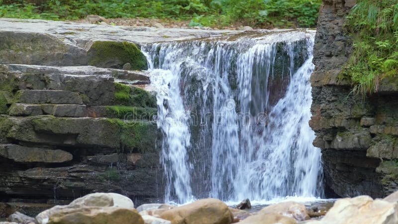 Chute d'eau sur la rivière de montagne avec de l'eau de mousse blanche tombant de la formation rocheuse dans la forêt d'été clips vidéos