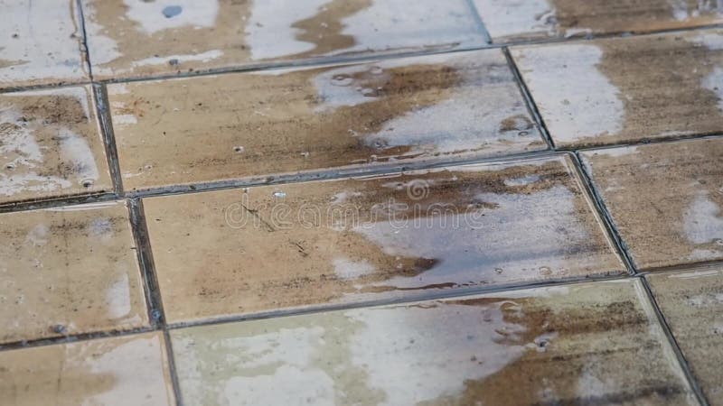 Chute de gouttes de pluie sur le trottoir de dalle La réflexion du ciel et des silhouettes troubles sur la surface humide