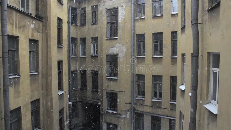 Chutes de neige de l'hiver dans la cour de la maison dans la perspective d'un vieil immeuble résidentiel à plusieurs niveaux avec banque de vidéos