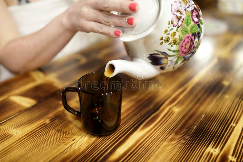 Chá de derramamento da mulher do bule cerâmico imagem de stock Chá de derramamento da mulher do bule cerâmico imagem de stock