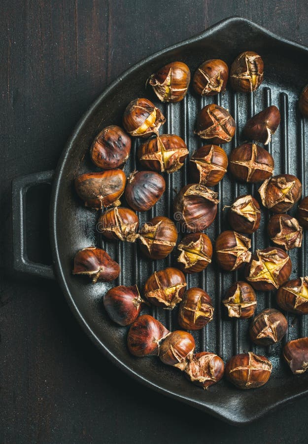 Châtaignes rôties en grillant la casserole au-dessus du fond en bois foncé images stock Châtaignes rôties en grillant la casserole au-dessus du fond en bois foncé images stock