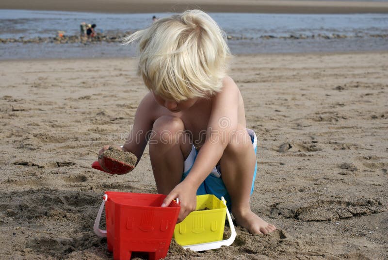 Blonde haired boy playing on the sand on skegness beach. Blonde haired boy playing on the sand on skegness beach