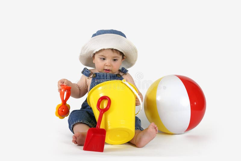 Beautiful baby girl in denim outfit and sunhat playing with beach toys. Beautiful baby girl in denim outfit and sunhat playing with beach toys.