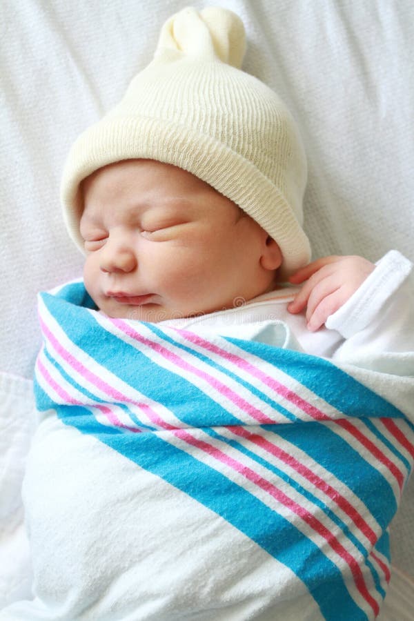 Newborn baby asleep, swaddled in hospital blanket and wearing a hat. Newborn baby asleep, swaddled in hospital blanket and wearing a hat