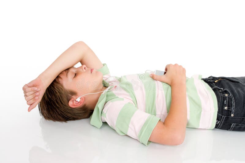A young boy lying down listening to music on a digital portable mp3 player. A young boy lying down listening to music on a digital portable mp3 player.