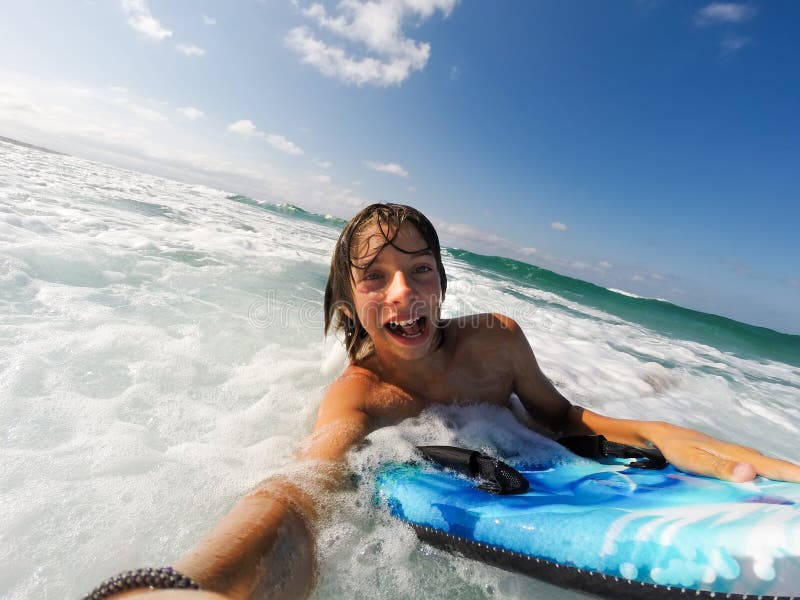 Chłopiec cieszy się jadący fala z surfboard obraz stock Chłopiec cieszy się jadący fala z surfboard obraz stock