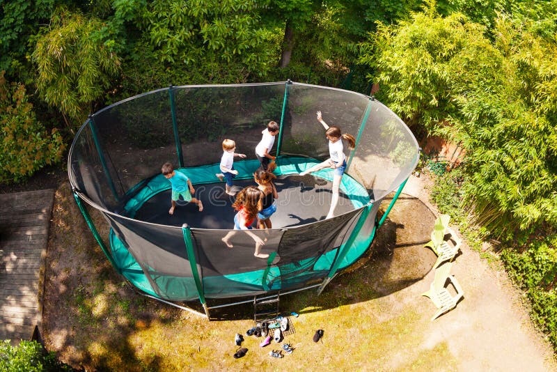 Chłopiec i dziewczyny skacze na trampoline w ogródzie obrazy royalty free Chłopiec i dziewczyny skacze na trampoline w ogródzie obrazy royalty free