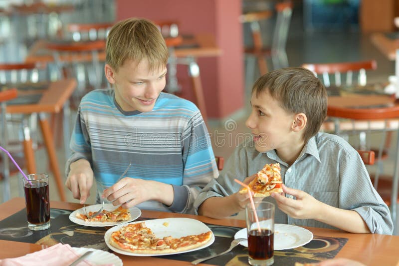 Portrait of two boys eating pizza in cafe. Portrait of two boys eating pizza in cafe.