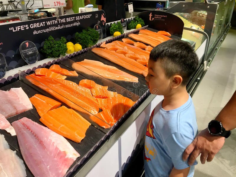 Chłopiec jest przyglądająca wiele kawałki surowa łosoś ryba dla bubla w supermarkecie Tajlandia Bangkok, Grudzień 22, 2018 fotografia stock Chłopiec jest przyglądająca wiele kawałki surowa łosoś ryba dla bubla w supermarkecie Tajlandia Bangkok, Grudzień 22, 2018 fotografia stock