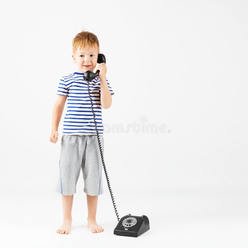 Chłopiec z retro telefonem przeciw bielowi obraz stock Chłopiec z retro telefonem przeciw bielowi obraz stock