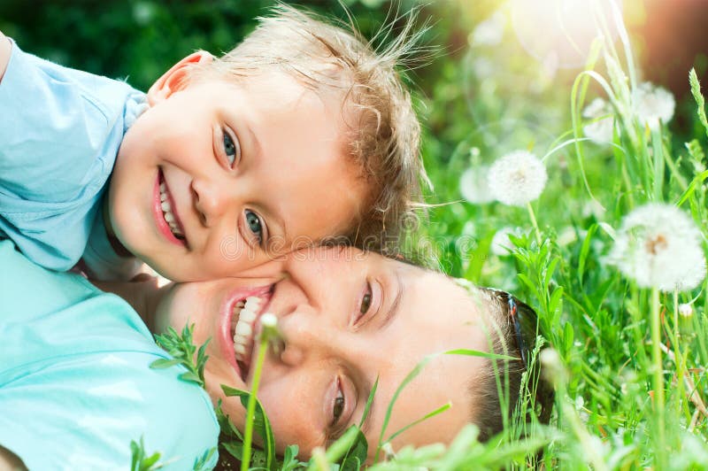 Cute 2 years old boy with mother lying in the grass at sunny summer day. Cute 2 years old boy with mother lying in the grass at sunny summer day