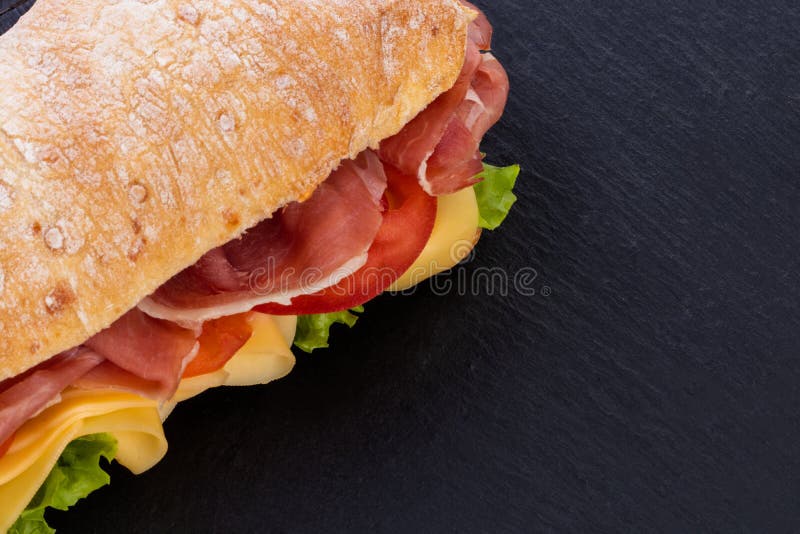 Ciabatta Sandwich with Lettuce , Prosciutto and Cheese Over Stone Background. Top View with Copy
