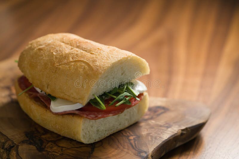 Ciabatta Sandwich with Salami and Mozzarella Cheese on Walnut Table