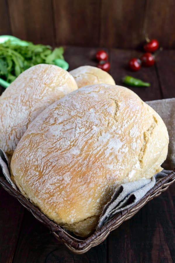 Ciabatta - vers gebakken Italiaans wit brood in de mand op een donkere houten achtergrond stock afbeelding Ciabatta - vers gebakken Italiaans wit brood in de mand op een donkere houten achtergrond stock afbeelding