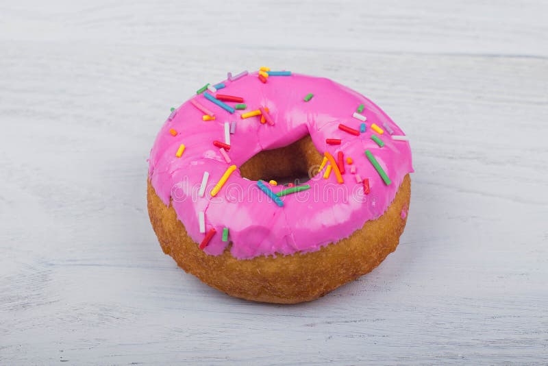 Ciambella con la glassa rosa su fondo di legno bianco fotografia stock libera da diritti Ciambella con la glassa rosa su fondo di legno bianco fotografia stock libera da diritti