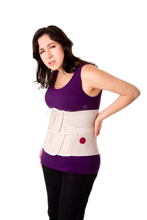 Woman in pain from back injury wearing an orthopedic body brace corset, isolated. Woman in pain from back injury wearing an orthopedic body brace corset, isolated.