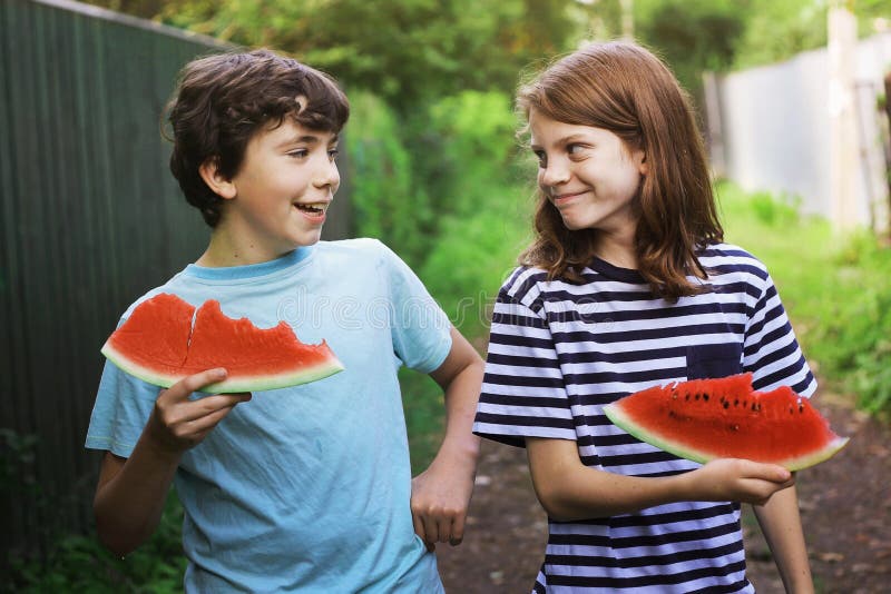 Cibo sorridente della fetta dell'anguria della tenuta dei ragazzi dell'adolescente fotografie stock libere da diritti Cibo sorridente della fetta dell'anguria della tenuta dei ragazzi dell'adolescente fotografie stock libere da diritti