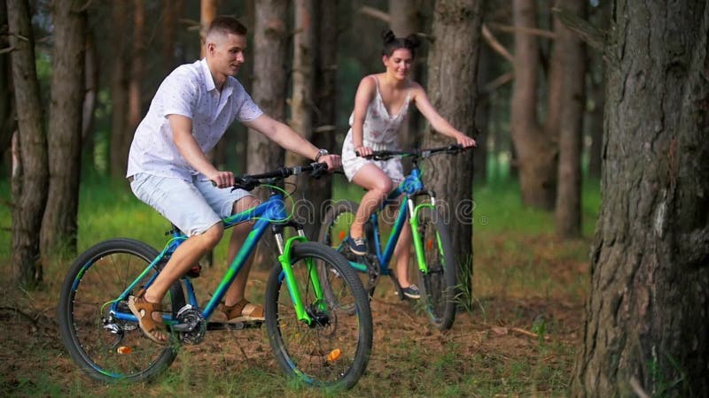 Ciclismo do homem novo e da mulher através da floresta do pinho